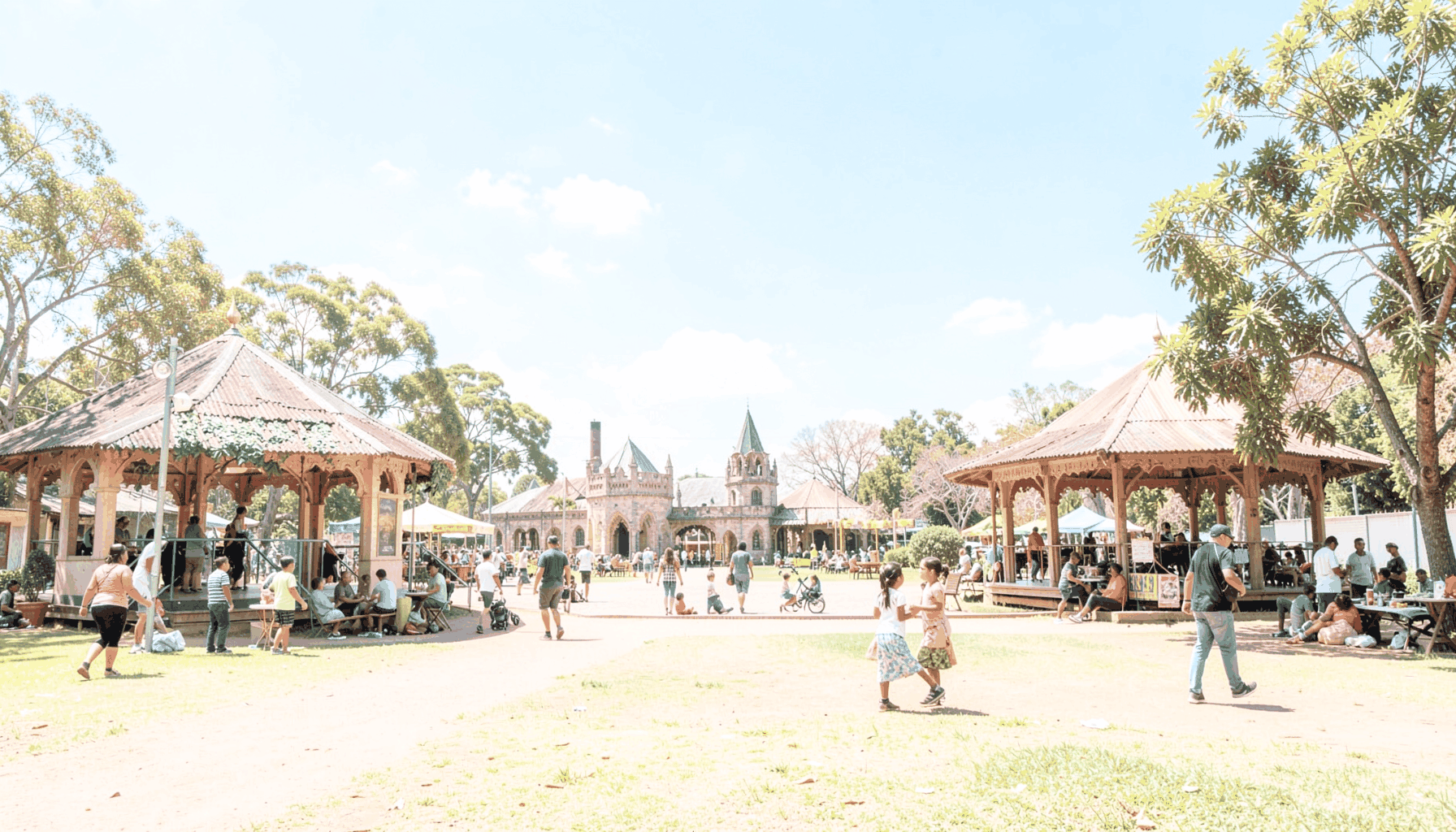 Sunlit parkland in Johannesburg with medieval pavilions, families enjoying the fair, and blue skies overhead