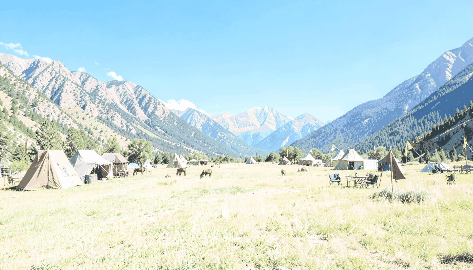 A Colorado meadow ringed by mountains, dotted with medieval tents and banners under a vivid blue summer sky